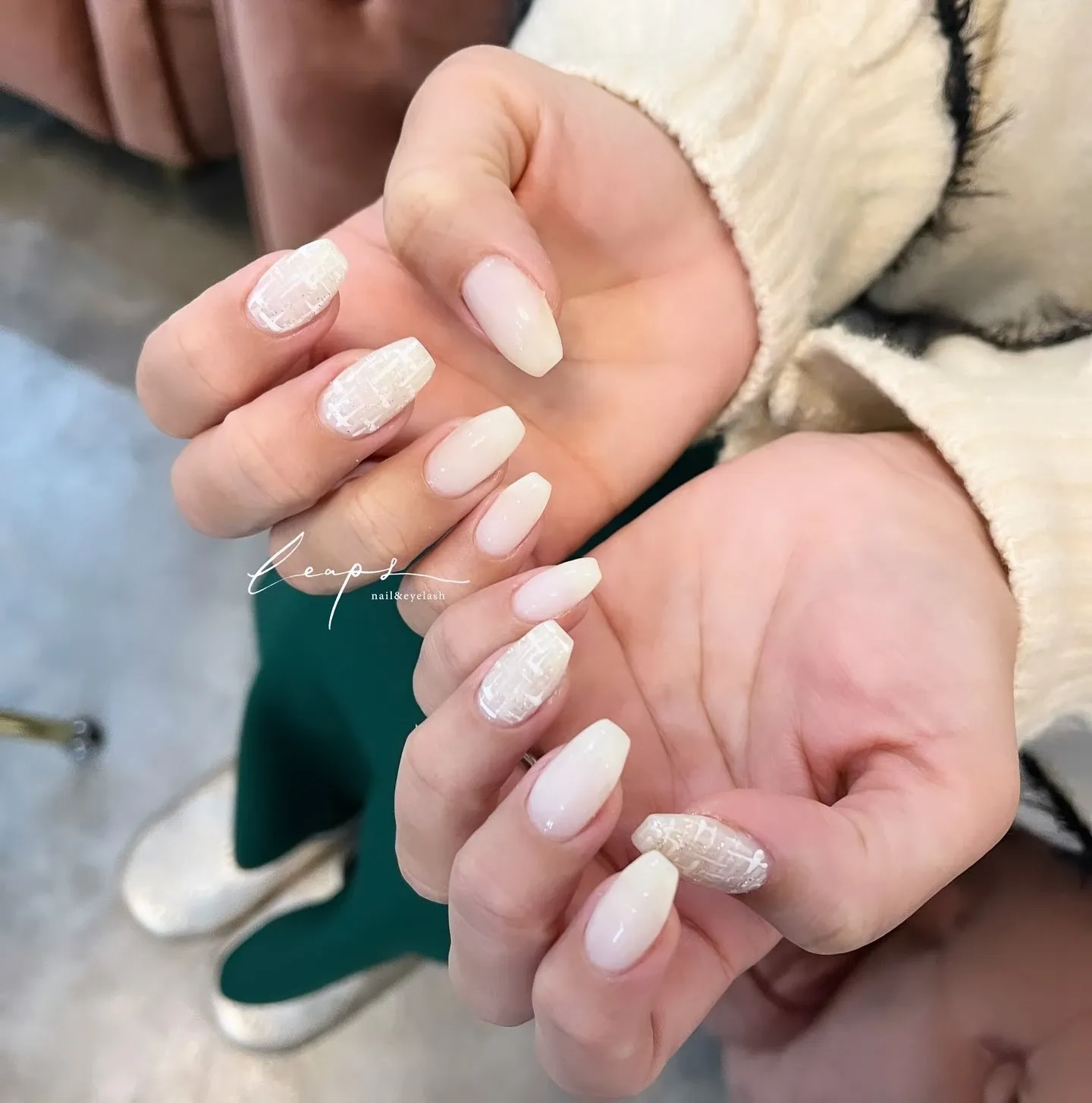 アイボリーホワイトのロングネイルに凹凸と細かなラメを重ねた両手